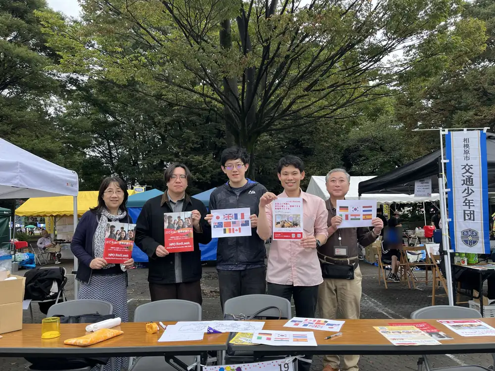 淵野辺公園の市民活動フェスタの会場で、Red Look のチラシや国旗を印刷した紙を持ってブースの前に並ぶメンバー