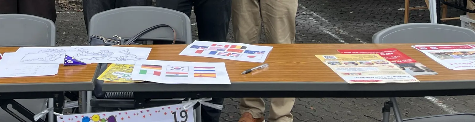 ブースの机の上に、各国の国旗を印刷した紙や、Red Look のチラシが並んでいる
